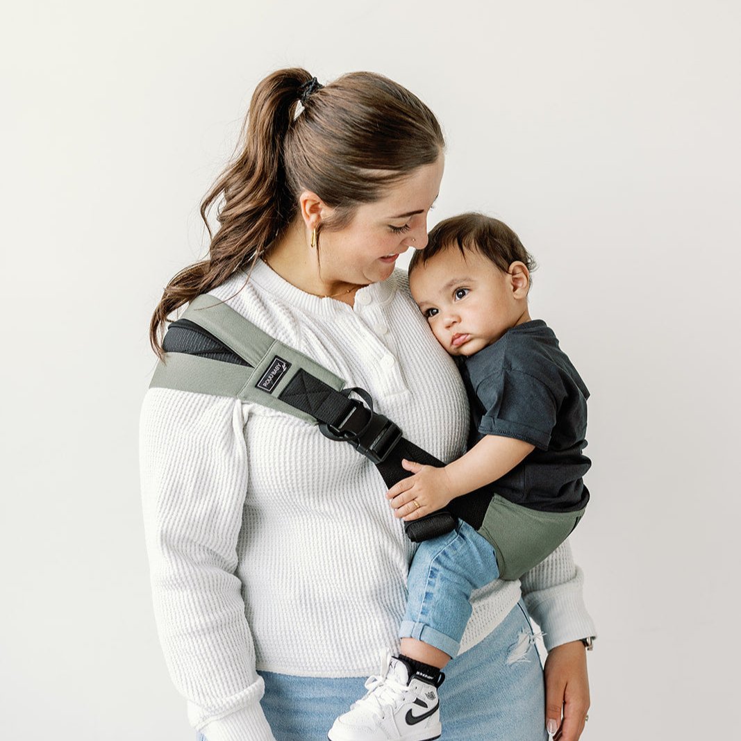 Parent carrying toddler in a Rouu Baby II ergonomic hip carrier