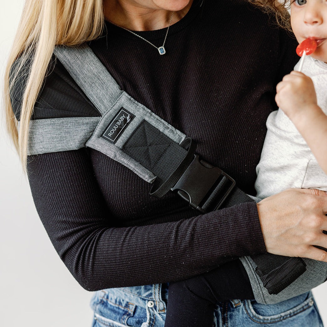 Parent carrying toddler in the Lux Graphite wipeable hip carrier