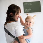 Parent laughing with toddler in a ROUU BABY carrier beside a ROUU BABY gift card